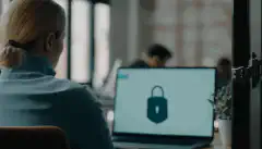 一个人坐在工作台前的图像，前景是一把安全锁，显示了确保工作台安全的重要性。